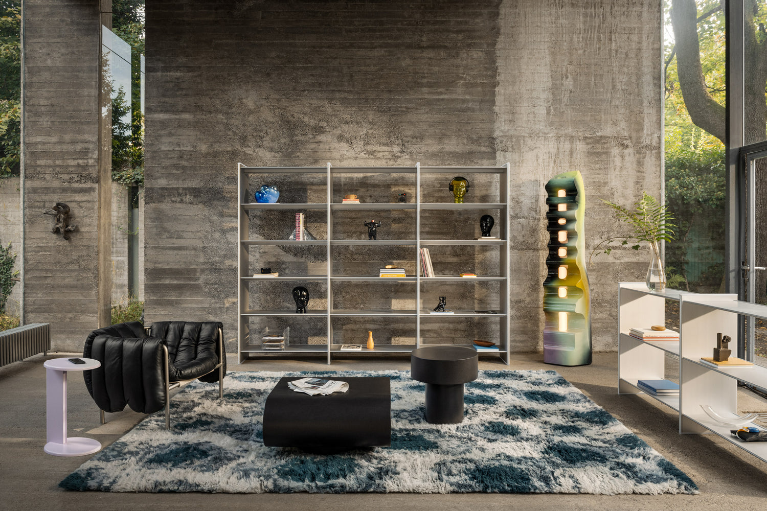 A living room scene featuring Lolly Side Table, Puffy Lounge Chair, Monster Rug, Stump Tables, and two T Shelf configurations.